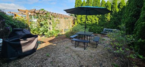 a table and chairs and an umbrella in a garden at 1 block to Kelowna General Hospital 2 blocks to Beach 1km to OUC 1km to Downtown Kelowna 20min to YLW in Kelowna