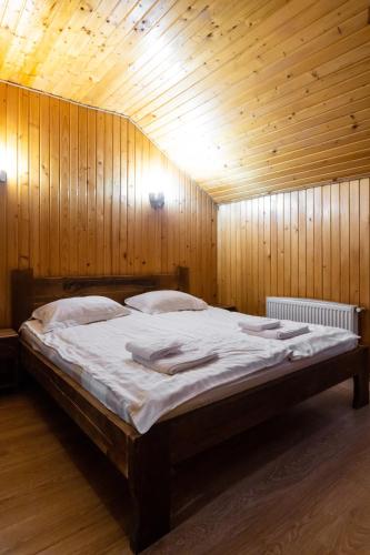 a large bed in a room with wooden walls at Готельний комплекс Парламент, Яблуниця in Yablunytsya