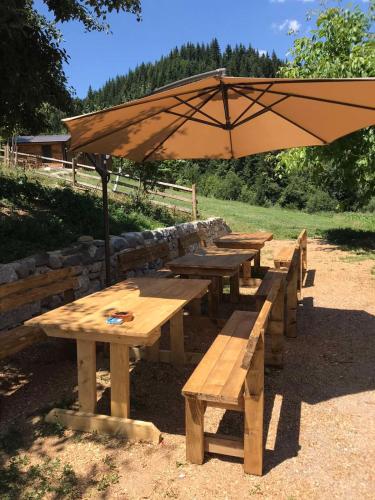 a group of wooden picnic tables with an umbrella at Bujtina Selimaj in Plav