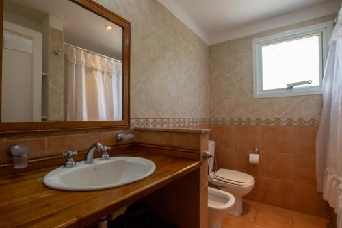 a bathroom with a sink and a toilet and a mirror at Complejo Viva Zapata in Mar de las Pampas