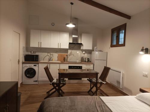 une cuisine avec des armoires blanches et une table et des chaises dans l'établissement Iris Garden Cottage, à Saint-Germain-en-Laye