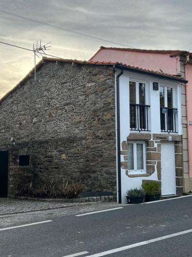a house with a brick wall next to a street at A Casiña do Rey Casita junto a la playa de Cabañas in Cabañas