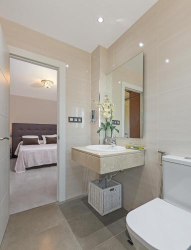 a bathroom with a sink and a bed and a mirror at Villa Granada Garden Deluxe in Monachil