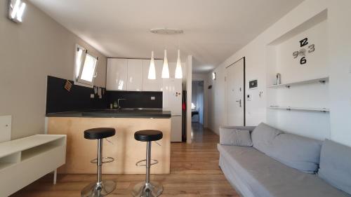 Il comprend une cuisine et un salon avec un canapé et un tabouret. dans l'établissement Ultimo piano con terrazzo e posto auto, à Zola Predosa