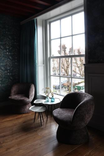 a living room with two chairs and a table and a window at Stadshotel Geertruidenberg in Geertruidenberg