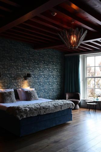 a bedroom with a large bed and a chandelier at Stadshotel Geertruidenberg in Geertruidenberg