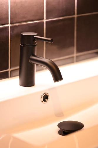 a bathroom sink with a black faucet at Stadshotel Geertruidenberg in Geertruidenberg