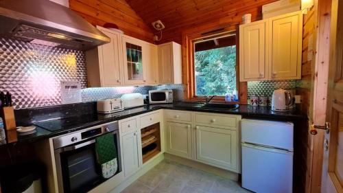 eine Küche mit weißen Schränken und schwarzen Arbeitsplatten in der Unterkunft Bramble Bank Gisburn Forest Lodge in Skipton