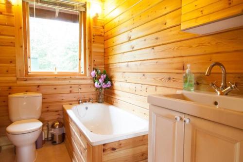 ein Badezimmer mit Badewanne, Toilette und Waschbecken in der Unterkunft Bramble Bank Gisburn Forest Lodge in Skipton