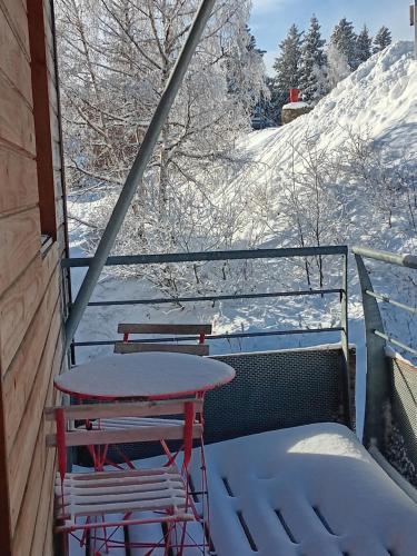 a table and two chairs on a balcony covered in snow at Les Arolles E23, classé 3 étoiles à Chamrousse 1700 in Chamrousse