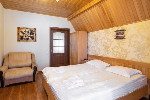 a bedroom with a bed and a chair at Готельний комплекс Парламент, Яблуниця in Yablunytsya