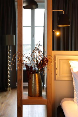 a vase with a plant on a shelf in a bedroom at Stadshotel Geertruidenberg in Geertruidenberg