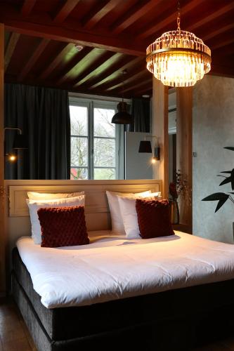 a bedroom with a large bed with a chandelier at Stadshotel Geertruidenberg in Geertruidenberg