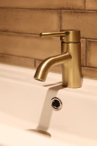 a bathroom sink with a brass faucet at Stadshotel Geertruidenberg in Geertruidenberg