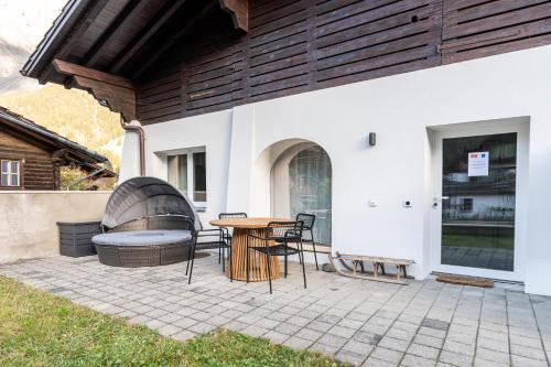 a patio with a table and chairs and a building at Cute & cozy oasis, private afternoon sun terrace in Kandersteg