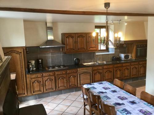une cuisine avec des armoires en bois et une table avec des chaises dans l'établissement Le Lavandin Gite familial 10 -12p, à Vireux-Wallerand