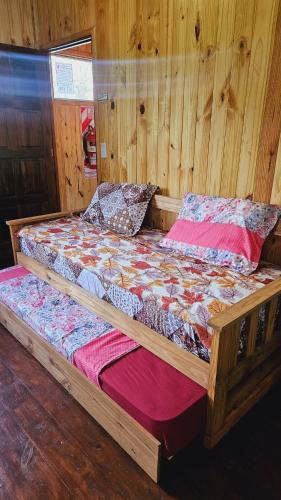 ein Holzbett in einem Zimmer mit Holzwänden in der Unterkunft Cabañas Flores de Lapacho Iguazu in Puerto Iguazú