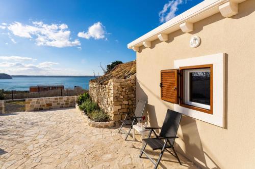 a building with two chairs and a window on it at MY DALMATIA - Sea view holiday home Fortica in Rtina
