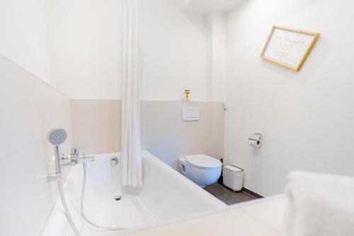 a white bathroom with a tub and a toilet at Unique Penthouse with Gallery and Mountain View in Kandersteg