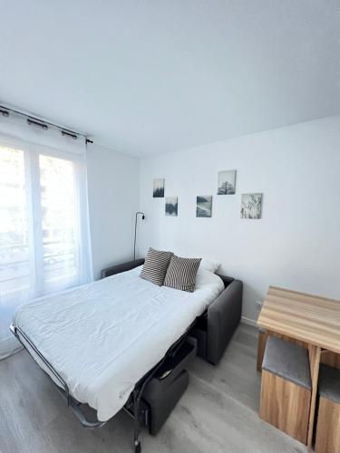 une chambre blanche avec un lit et une table dans l'établissement Cosy home stade de France CDG airport, à Saint-Denis
