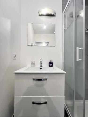 une salle de bain blanche avec un lavabo et une douche dans l'établissement Cosy home stade de France CDG airport, à Saint-Denis
