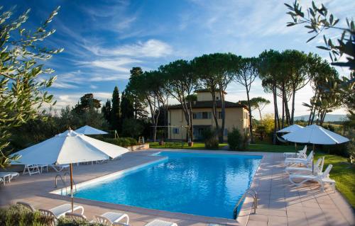 a swimming pool with umbrellas and chairs and a house at La Certaldina in Certaldo