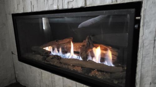 a fireplace with meat and flames in it at Airdrie Modern Walkout Bsmt Suite with Hot Tub in Airdrie