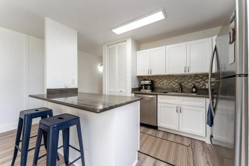 a kitchen with white cabinets and blue stools at Welcome to Gorgeous Hideout – Your Serene Hawaiian Escape! in Kahuku