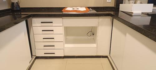 a kitchen with white cabinets and a black counter top at Casa com piscina in Maceió