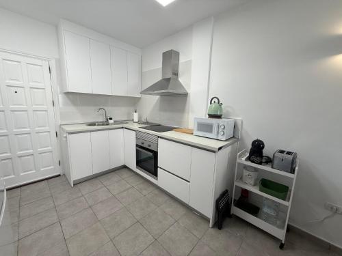 a kitchen with white cabinets and a sink and a microwave at Apartamento Playa Las Vistas in Arona
