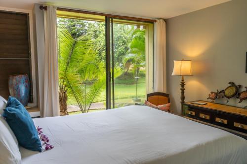 a bedroom with a bed and a large window at Rare 2 Bedroom & Loft Townhouse on the North Shore in Kahuku