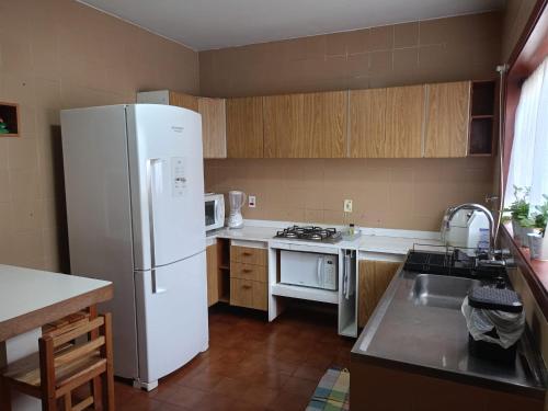 a kitchen with a white refrigerator and a stove at Casa inteira no Centro de Jacareí próximo à São José dos Campos in Jacareí