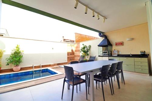 a dining room with a table and chairs and a swimming pool at 33hosts | Splendor Casa 10 · Serviço de Praia em Juquehy c/ Piscina Aquecida in São Sebastião