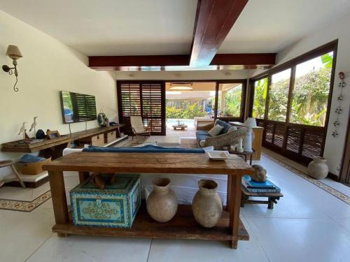 a living room with a table and vases on the floor at Casa Conforto Barra do Una in São Sebastião