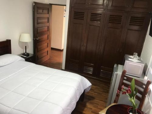 a bedroom with a large white bed and wooden cabinets at Altura Rooms & Suites in Quito