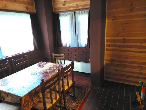 a dining room with a table and chairs and windows at Kablar Lazino Brdo in Čačak