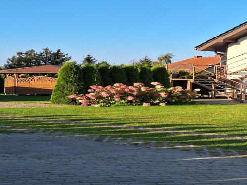 a lawn with pink roses and a house with a building at Apartment in Stepnica near Szczecin Lagoon in Stepnica