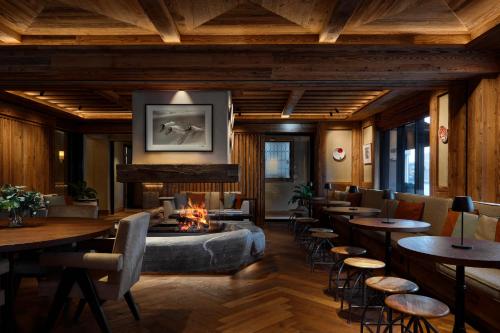 a restaurant with a fireplace and tables and chairs at Miiro The Mansard in Gstaad