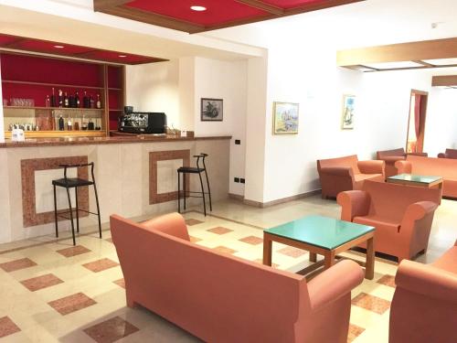 una sala de espera con sillas naranjas y un bar en Villaggio Hotel Ripa, en Rodi Garganico