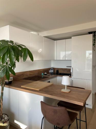 une cuisine avec des placards blancs et une table avec une lampe dans l'établissement 2 pièces, vue mer panoramique, à Menton