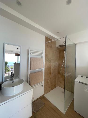 une salle de bain blanche avec un lavabo et une douche dans l'établissement 2 pièces, vue mer panoramique, à Menton