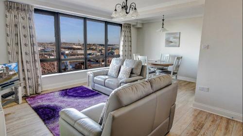 a living room with a couch and chairs and a large window at Dockside Penthouse - Free Parking in Galway