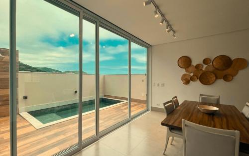 a dining room with a table and a large window at Casa 14 · 4 Suítes | Piscina Privativa e Serviço De Praia in São Sebastião