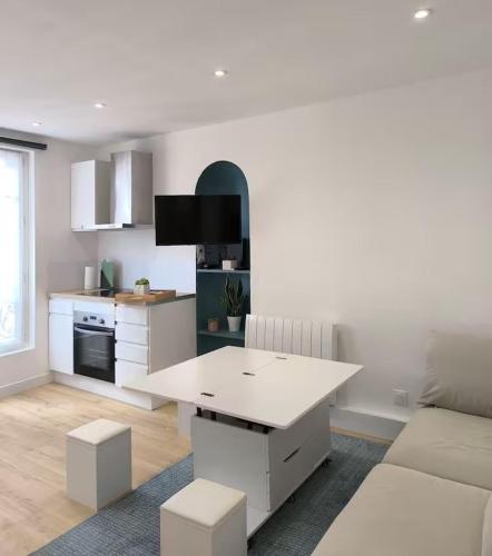 - une cuisine blanche avec une table blanche et un canapé dans l'établissement Appartement cosy - Saint Louis Paris 10, à Paris