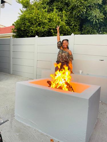 a woman standing in front of a fire pit at Maita Guest in Cape Town