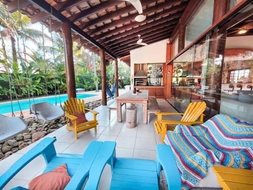 eine Terrasse mit Stühlen, einem Tisch und einem Pool in der Unterkunft Casa Paraiso Praiano 2 minutos da praia · Barra do Una | Paraíso praiano a 120m da praia in São Sebastião