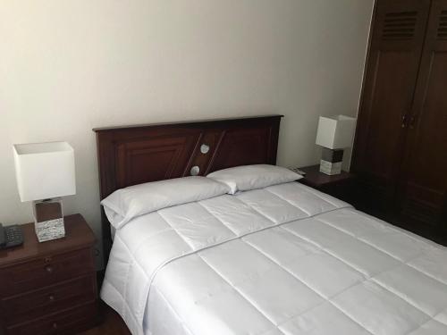 a bedroom with a bed with two nightstands and two lamps at Altura Rooms & Suites in Quito