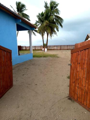 a wooden gate in front of a beach with palm trees at Casa Azul Miguel de la Borda in Miguel de la Borda