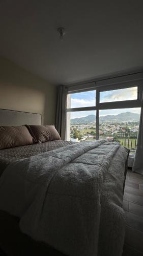 a bedroom with a bed and a large window at Apartamento Adrano, Cerca de La Antigua Guatemala in Guatemala