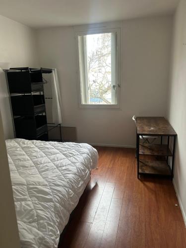 une chambre avec un lit, une table et une fenêtre dans l'établissement Agréable Chambre Confortable 2, à Asnières-sur-Seine